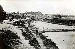高輪付近。人が立っている場所から右が海。はしけとその先に堤防がある。左は東海道（現在の国道1号線）