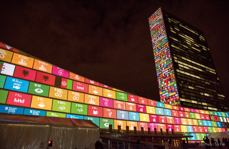 図版:2015年,SDGsが採択されたときの様子。国連本部の壁にプロジェクションマッピングで17のゴールが彩られた