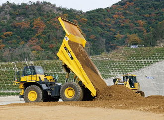 写真： 自動ダンプトラックと自動ブルドーザの連動作業