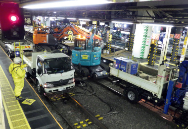 図版:夜間工事で軌陸式の工事用車両が並ぶ駅構内(現場撮影)