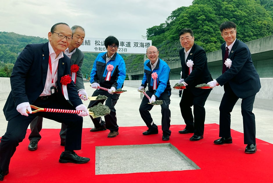 図版：最終コンクリートを投入する鹿島・尾崎支店長（右から2人目）